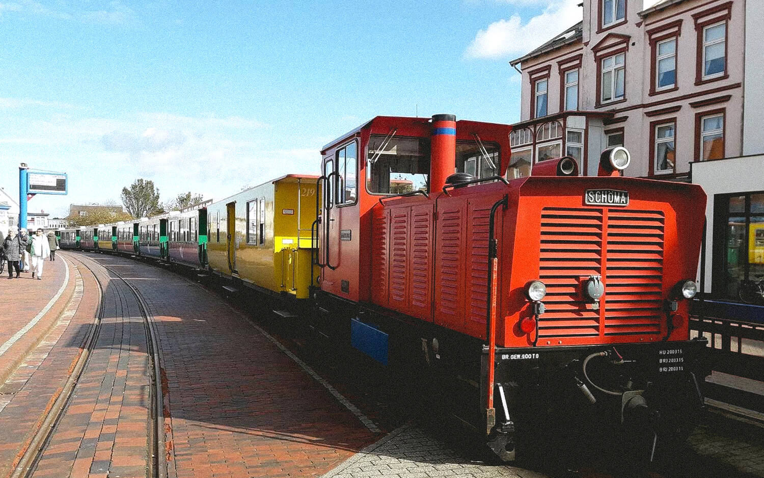 Borkumer Kleinbahn, Rote Lock mit gelben Wagons an einem Bahnsteig